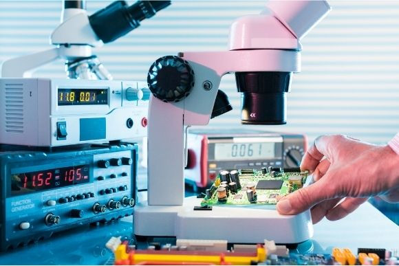 Ispettore controllo qualità analizza un circuito stampato al microscopio