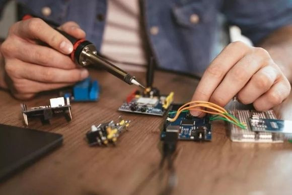 Tecnico esperto salda degli assemblaggi elettrici ed elettronici su un circuito stampato