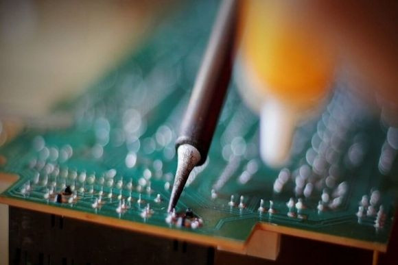 Tecnico esperto salda degli assemblaggi elettrici ed elettronici su un circuito stampato